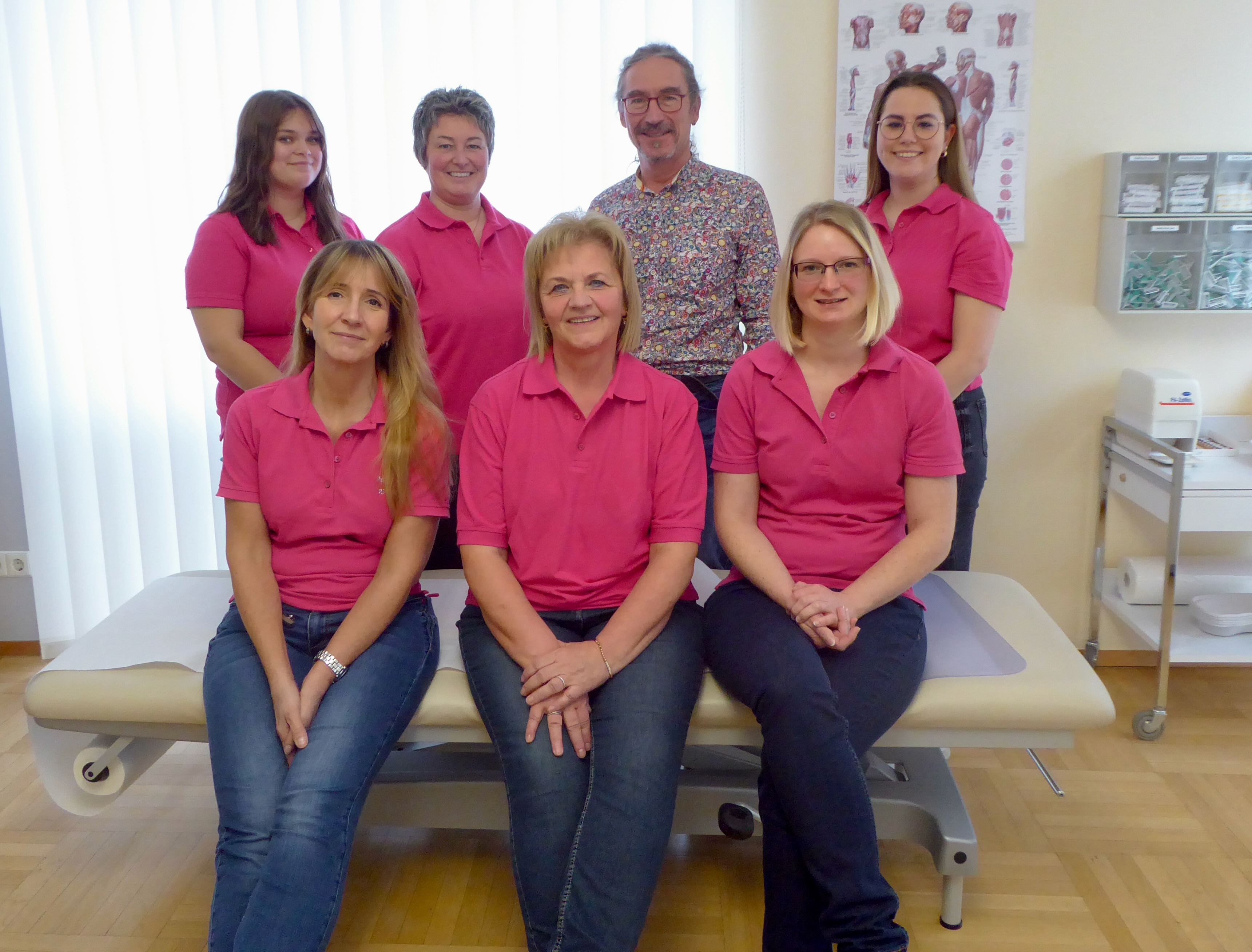 Praxisteam mit Arzt und medizinischen Fachangestellten auf einer Behandlungsliege in der Arztpraxis - Ärztestellen in kollegialem Umfeld