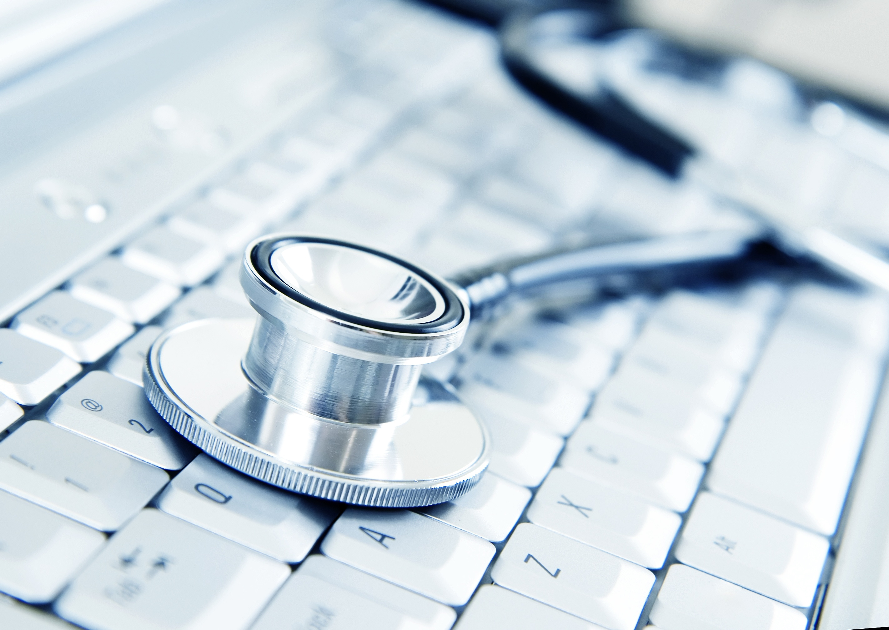 Ein Stethoskop liegt auf einer weißen Computertastatur - Sinnbild für digitale Arztpraxis, medizinische Software und den Einsatz von Künstlicher Intelligenz im Gesundheitswesen