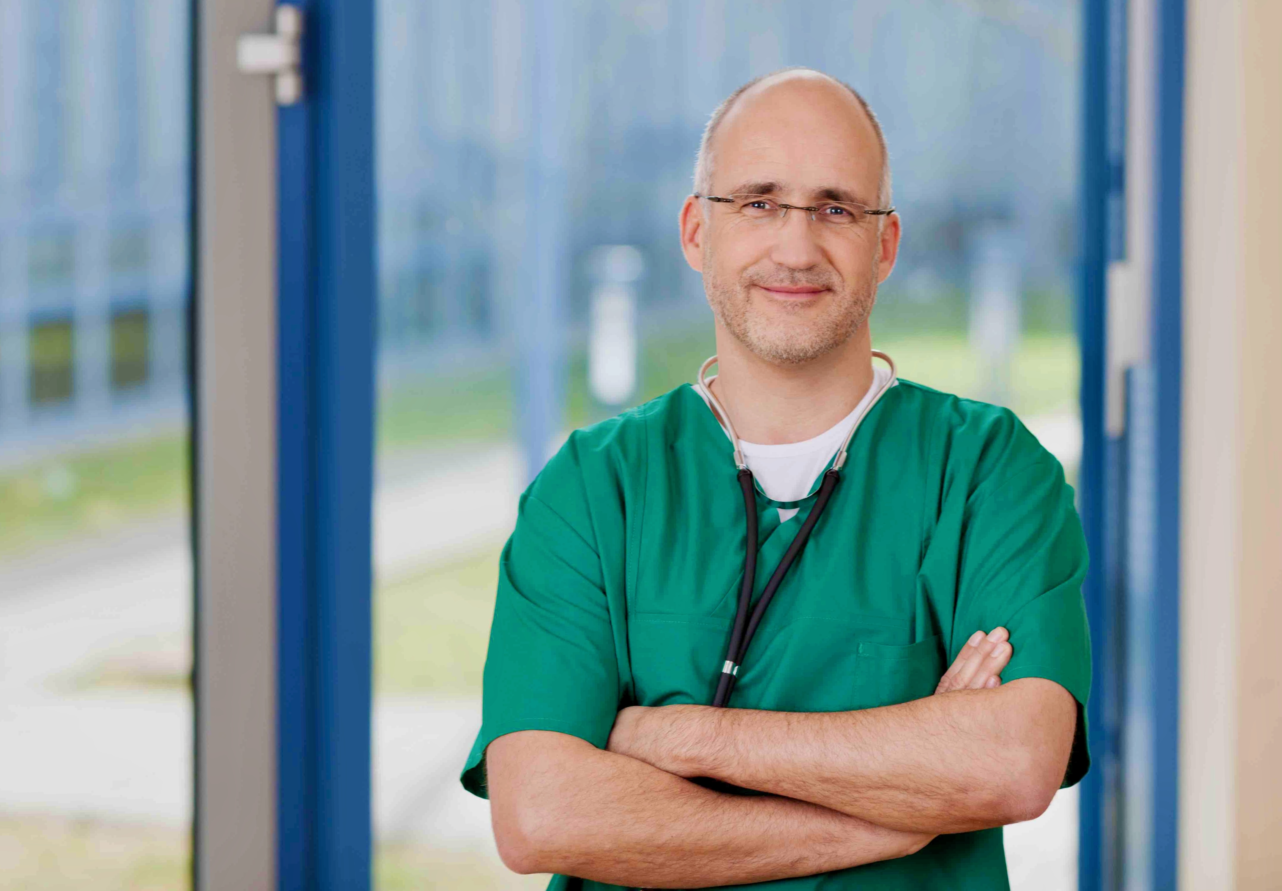 Arzt in grüner Arbeitskleidung als Symbolbild für kostenlose Kollegenbehandlung unter Ärzten