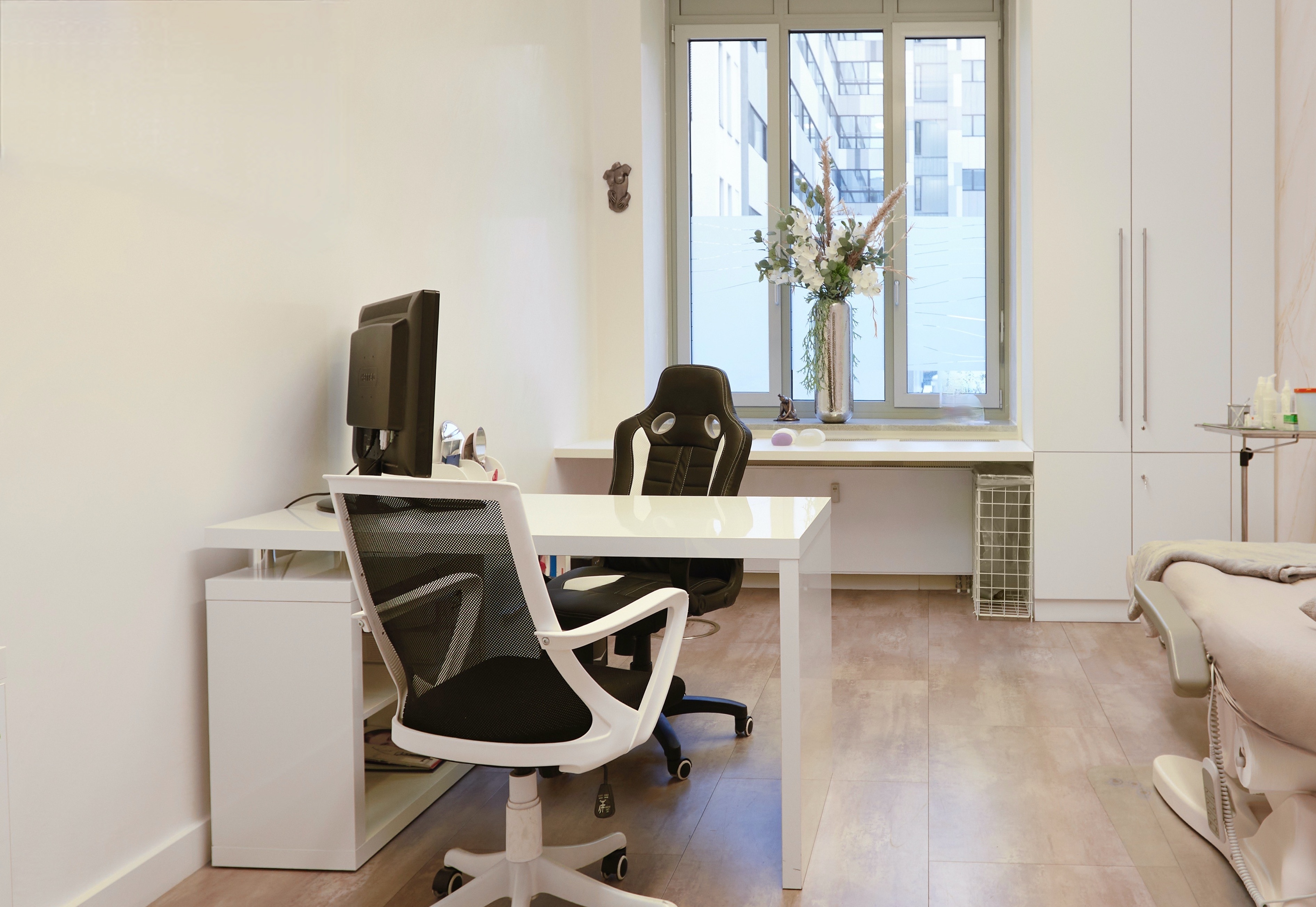 Modern eingerichtetes Sprechzimmer mit Schreibtisch und Behandlungsbereich vor einer Praxisübergabe